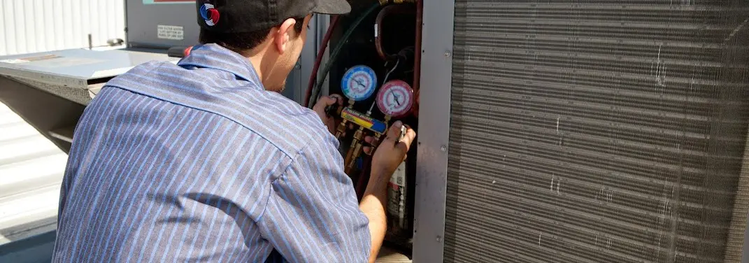HVAC technician servicing a condenser unit in Dubuque